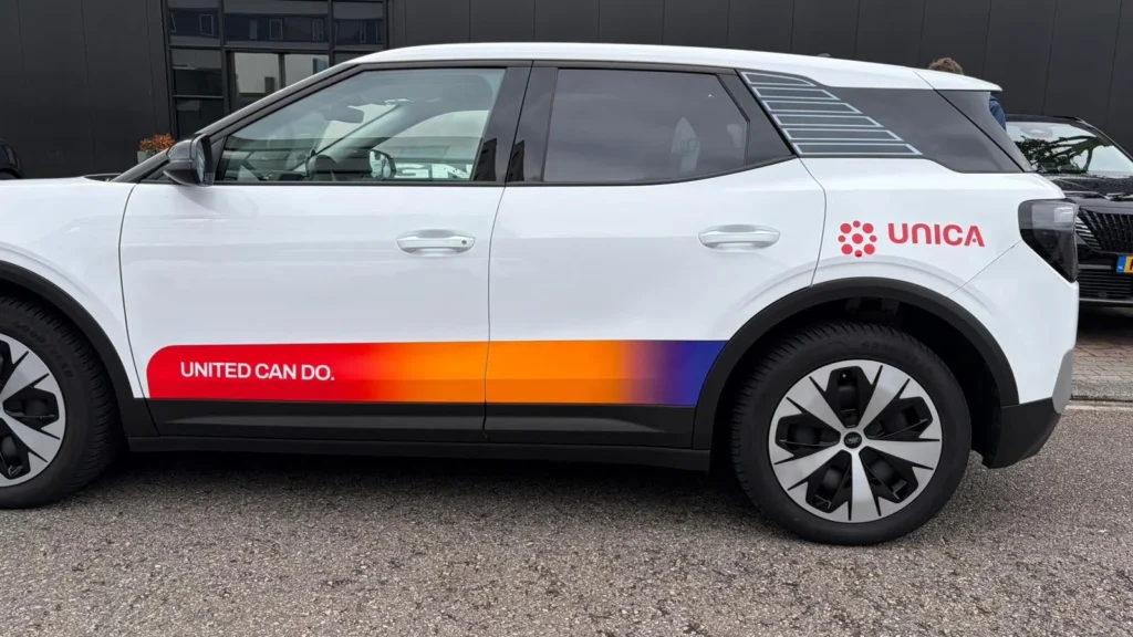 Zijaanzicht van een Unica personenauto met voertuigbelettering